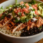 A delicious What Does a Chipotle Chicken Bowl Have?, black beans, cilantro-lime rice, fresh pico de gallo, guacamole, sour cream, and shredded lettuce, served in a white bowl.